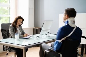 An injury victim in a wheelchair, with a neck brace and an arm sling, discussing their case with an experienced personal injury lawyer in Brookings.