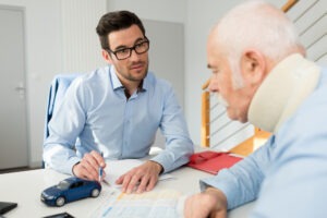 A car accident victim with a neck brace discussing his case with an experienced car accident lawyer in Watertown.