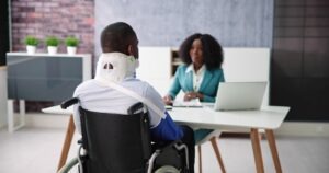 An injury victim in a wheelchair with a neck brace and an arm sling discussing their case with an experienced personal injury lawyer in Aberdeen.