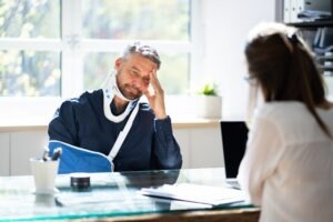 An injury victim with a neck brace and an arm sling discussing their case with an experienced personal injury lawyer in Mitchell.